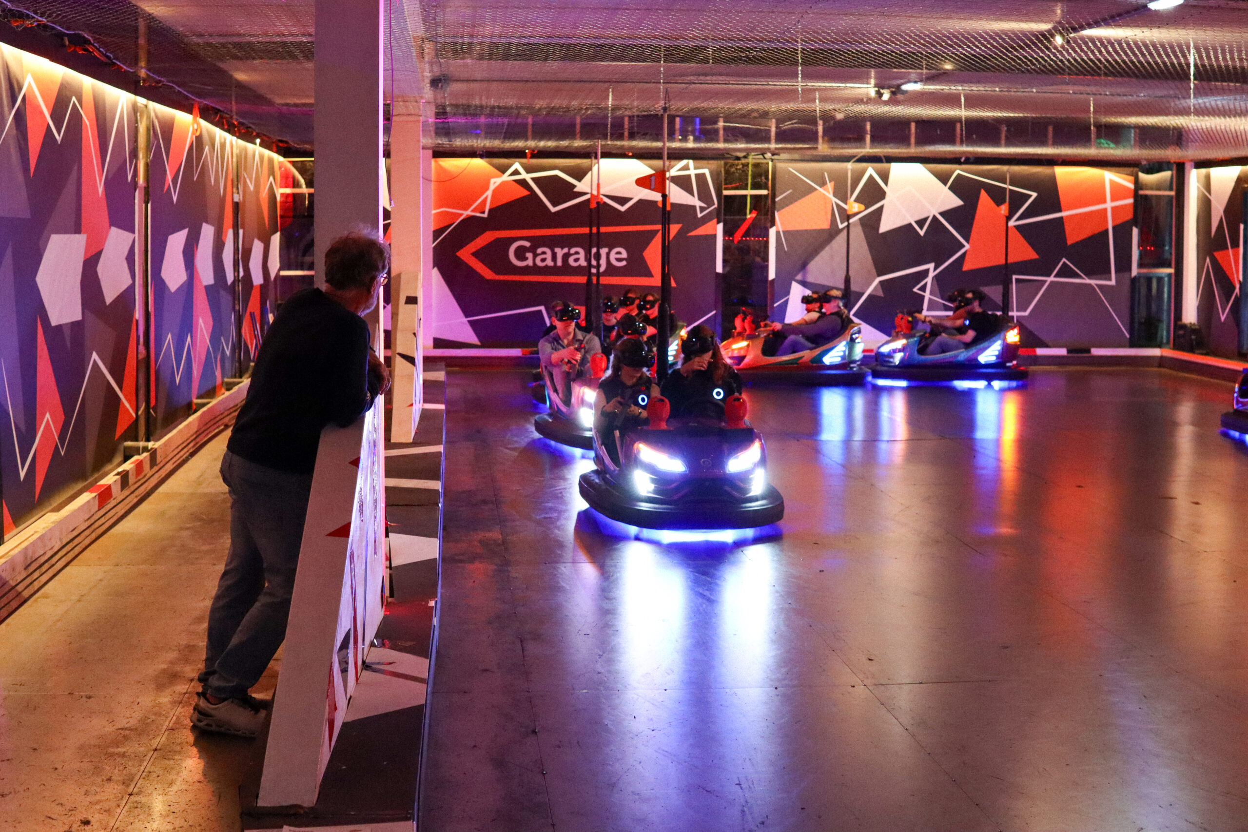 A wide image of a bunch of VR bumper cars and someone overlooking them