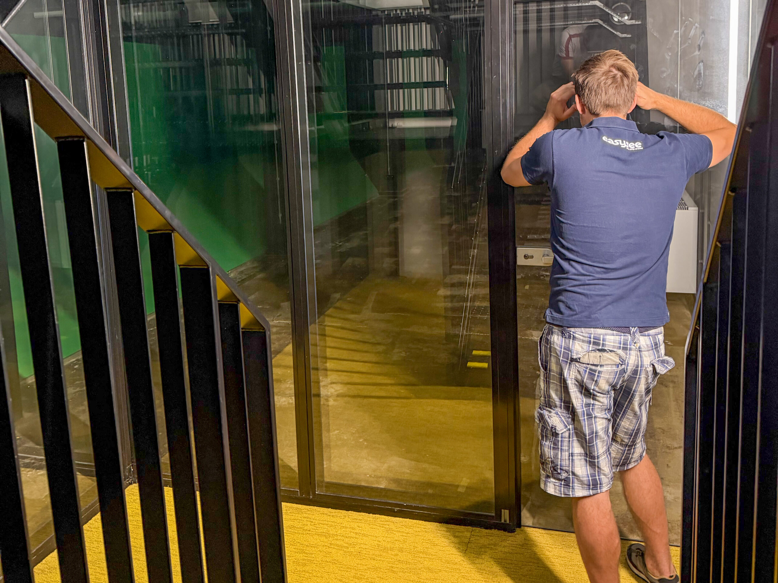 An employee looks closely through the glass doors into the designated space that will be transformed into the physical VR Experience Room.