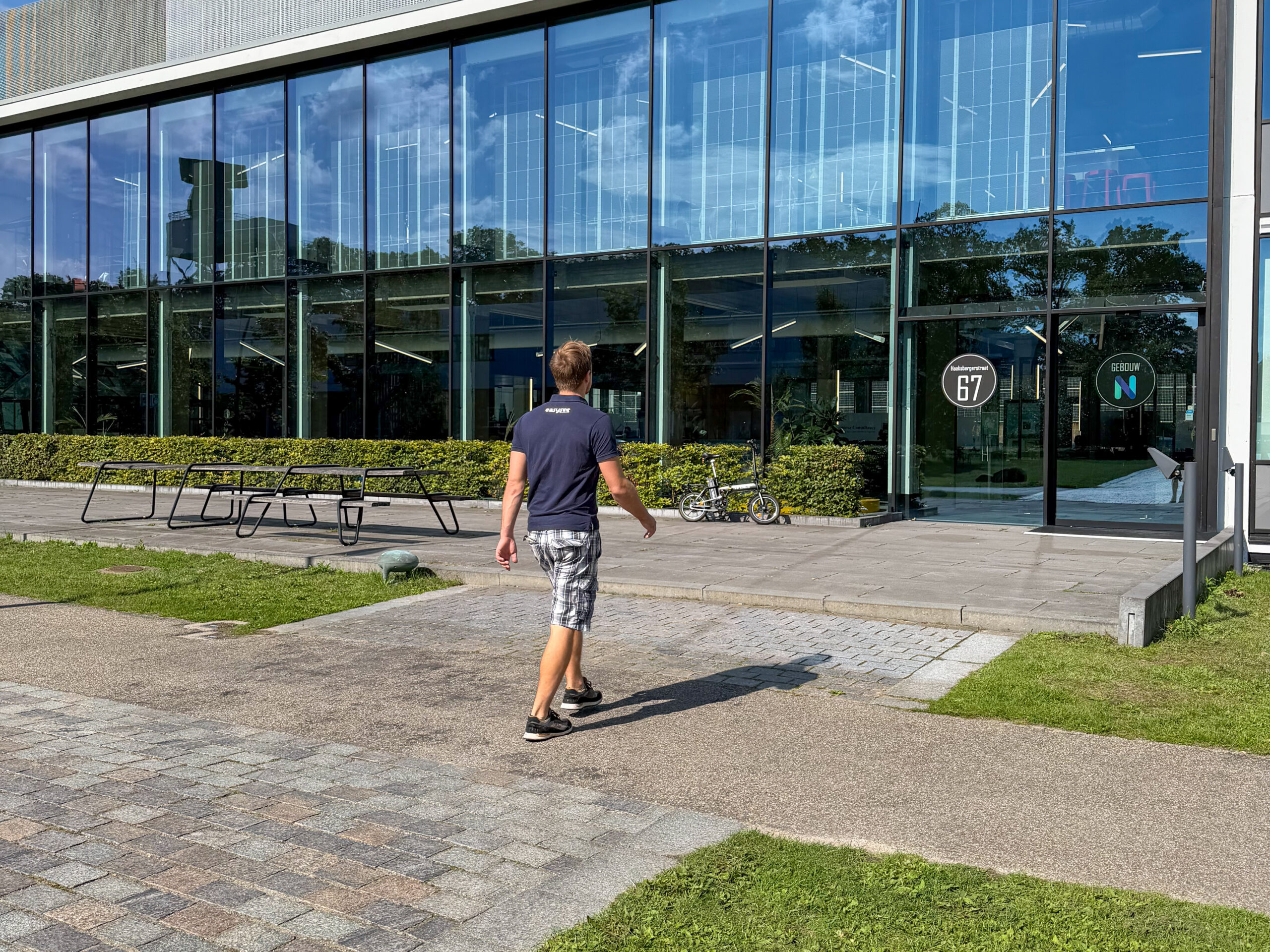 An Easysee employee walks outside towards the entrance of the modern glass office building where the new Experience Room will be realized.